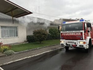 Feuerwehrauto vor brennendes Haus