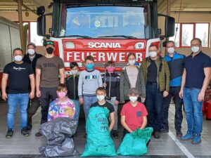 Kinder und Feuerwehrleute mit Müllsäcken